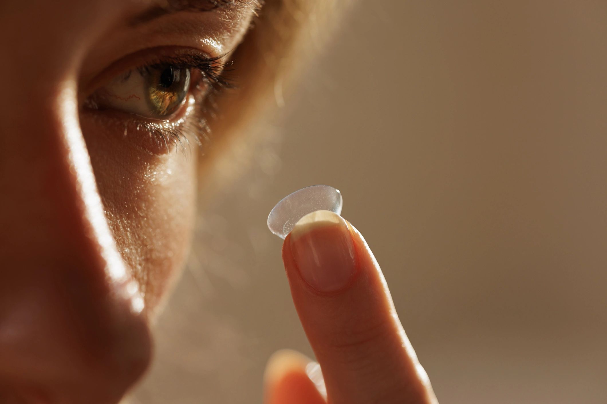 Close-up of a contact lens on a fingertip near an eye